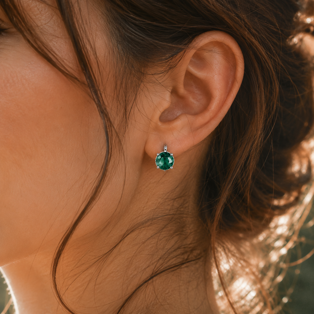 Close-up of an ear wearing a green gemstone earring with blurred background