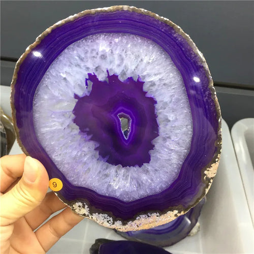 Close-up of a purple and white geode slice held by a hand.