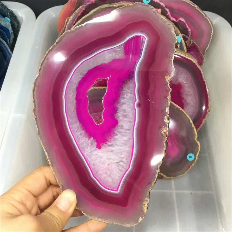 Pink and white geode slice held by a hand on a white surface