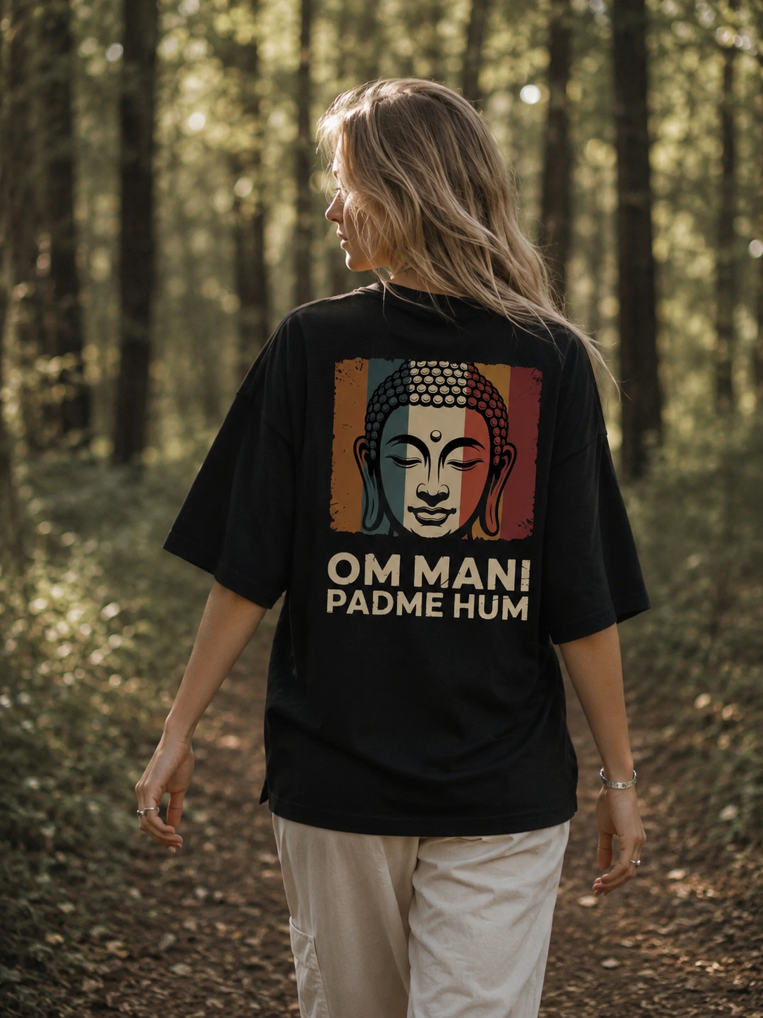 Person wearing a black t-shirt with a Buddha graphic and 'OM MANI PADME HUM' text in a forest setting