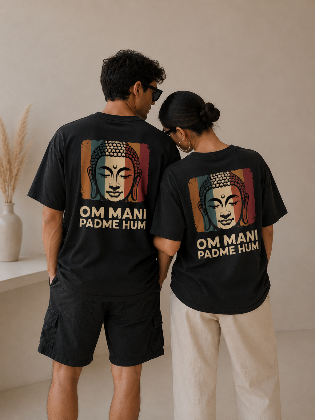 Two people wearing black t-shirts with a Buddha graphic and 'OM MANI PADME HUM' text.