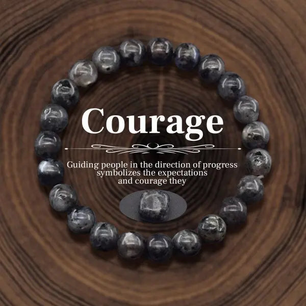 Black beaded bracelet with 'Courage' text on a wooden background