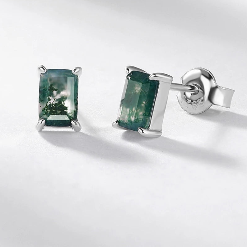 Silver earrings with green gemstones on a white background, featuring the brand 'WES'.