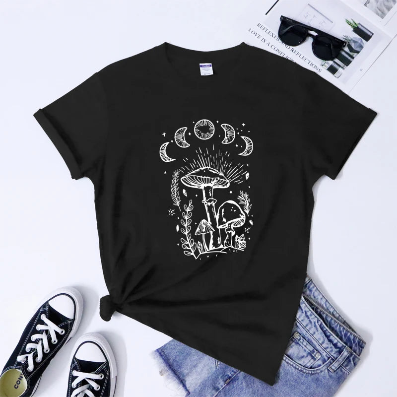 Black t-shirt with white graphic design on a white surface with shoes and jeans.