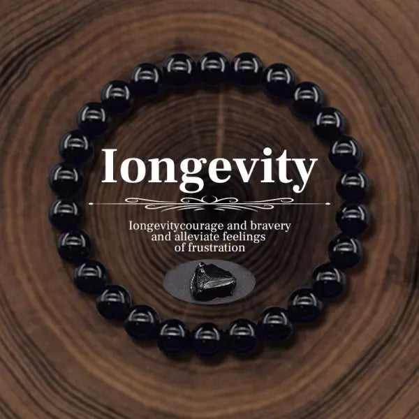 Black beaded bracelet with 'Longevity' text on a wooden background