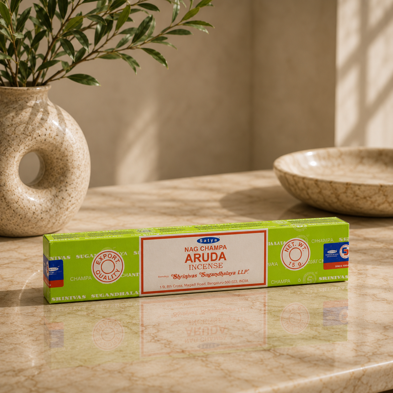 Box of Nag Champa Aruda incense on a marble surface with a plant and bowl in the background.