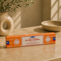 Box of Saiyna Divine Karma incense on a wooden surface with decorative items in the background