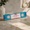 Box of Nag Champa Money Matrix incense on a marble surface with a plant in the background