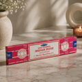 Box of Satya Nag Champa Indian Rose incense on a marble surface with a candle and vase in the background.